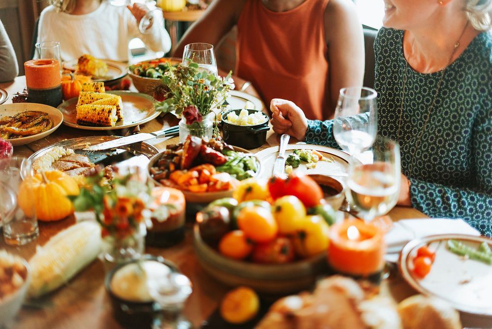 A diverse group enjoying a festive meal with colorful dishes, fresh vegetables, and drinks. The table is filled with vibrant…