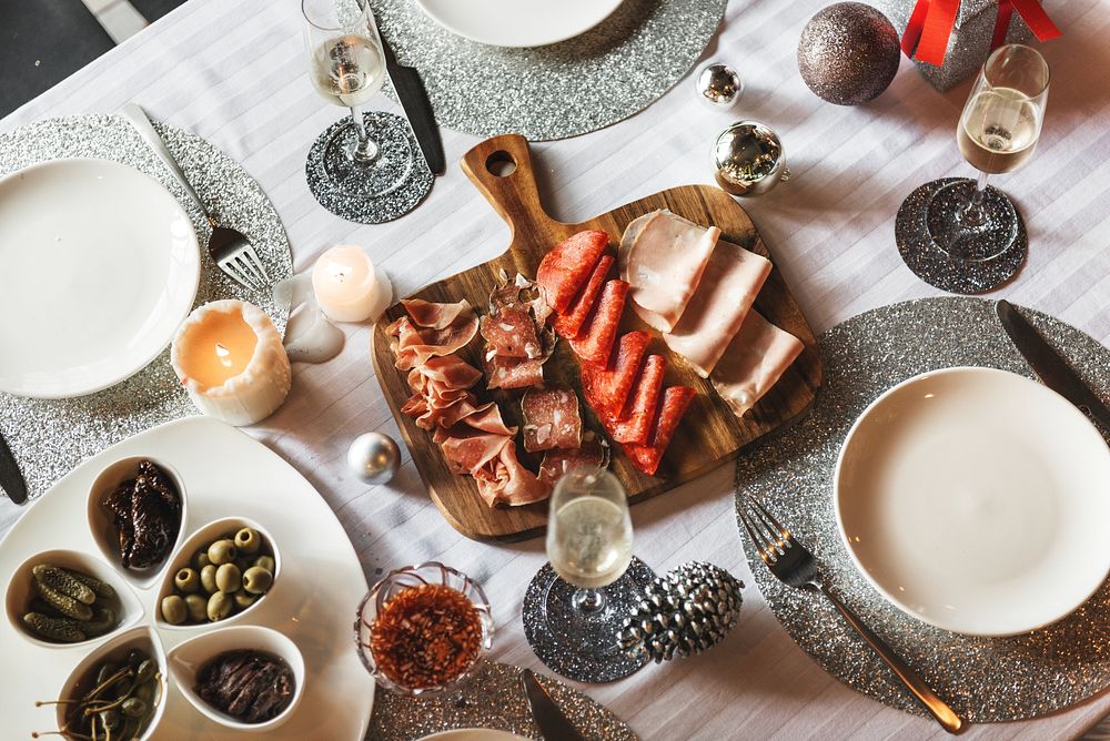 Festive table setting with charcuterie board, featuring meats, olives, and sparkling decor. Elegant dining with meats…