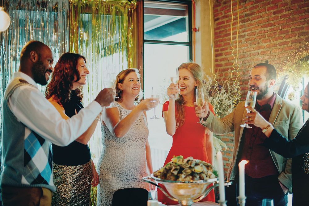 Group of diverse adults celebrating at a party. Smiling men and women, dressed elegantly, raise glasses. Festive atmosphere…