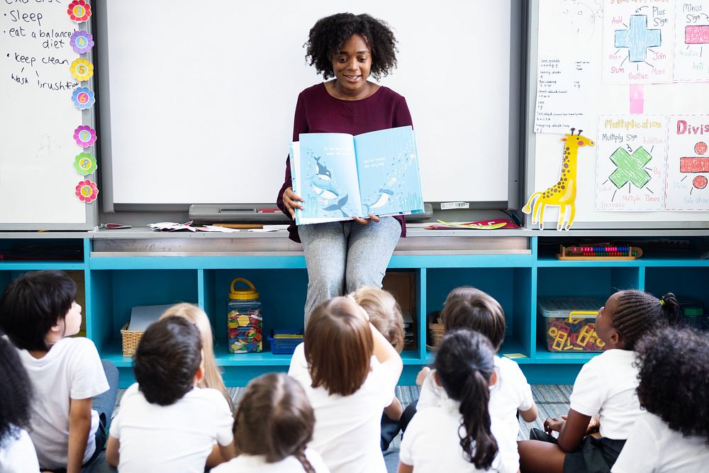 Teacher reading to diverse group of children. Classroom setting with teacher and students. Engaged children listening to…