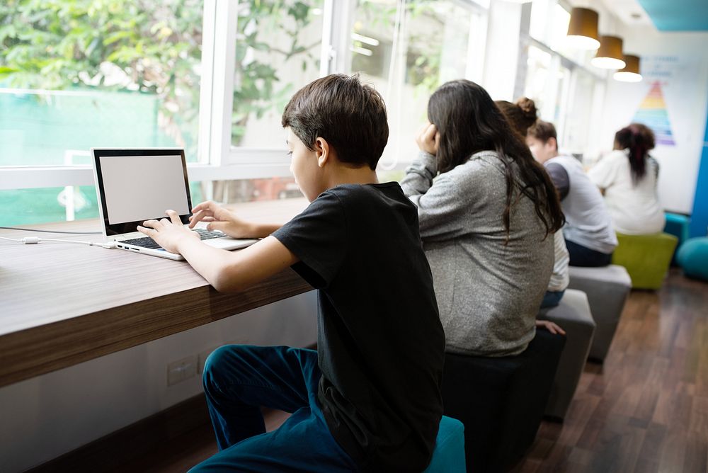 Students studying in a modern library. Young people focused on laptops. Diverse group learning in a bright, open space.…