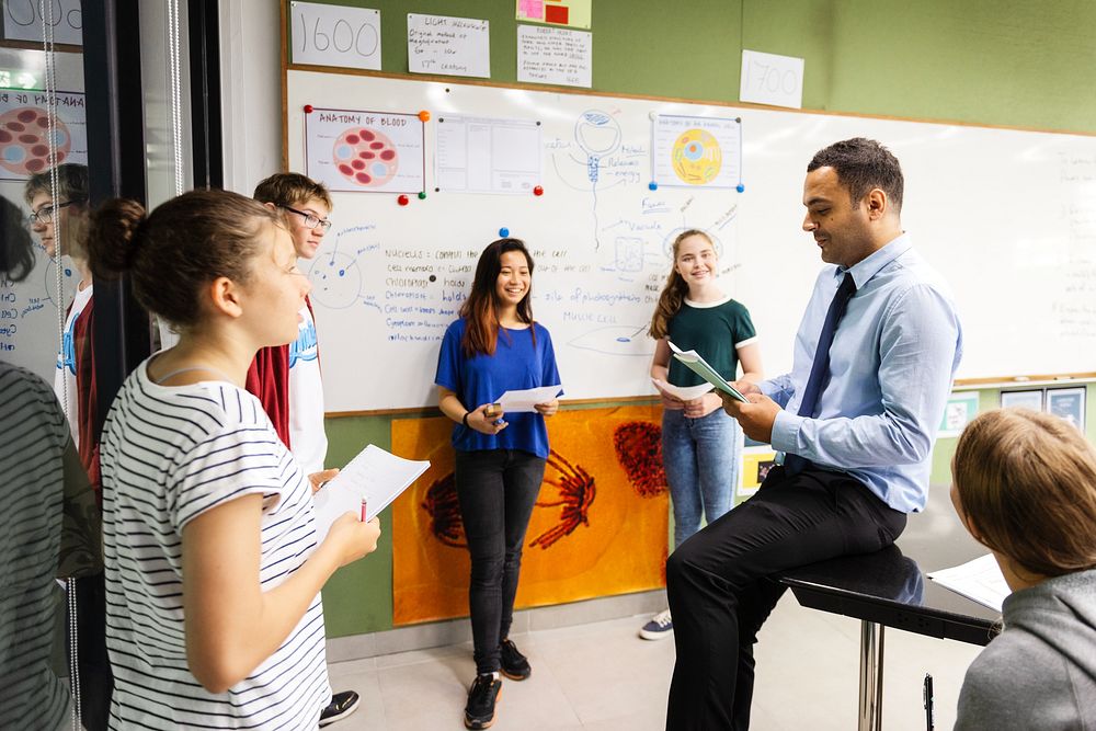 Group of students and a teacher in a classroom discussing. Diverse student group learning in class. Students learning…