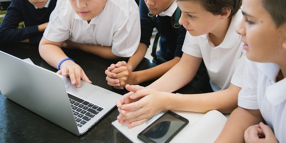 Group of student focus on laptop in online learning classroom, diverse students in school uniforms learn online. Diverse…