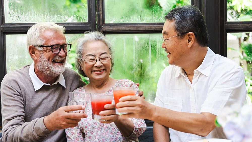 Group of diverse seniors enjoying a meal together, laughing and sharing drinks. Elderly friends, diverse gathering, joyful…