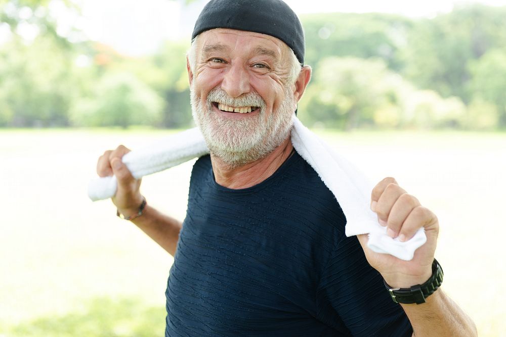 Happy senior man outdoors, smiling with a towel around his neck. Happy elderly man enjoying nature. Elderly man in casual…