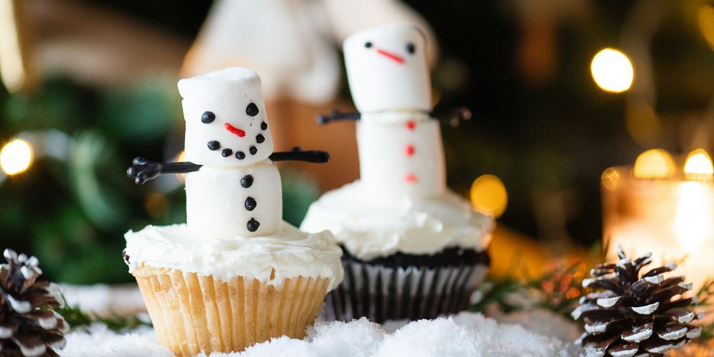 Festive cupcakes with marshmallow snowmen, surrounded by snow and pinecones. Snowmen cupcakes, holiday treats, and festive…