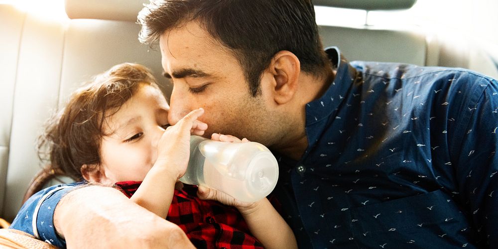 Father and child in a car. South Father kisses child. Child drinks from a bottle. Loving father, caring father, affectionate…