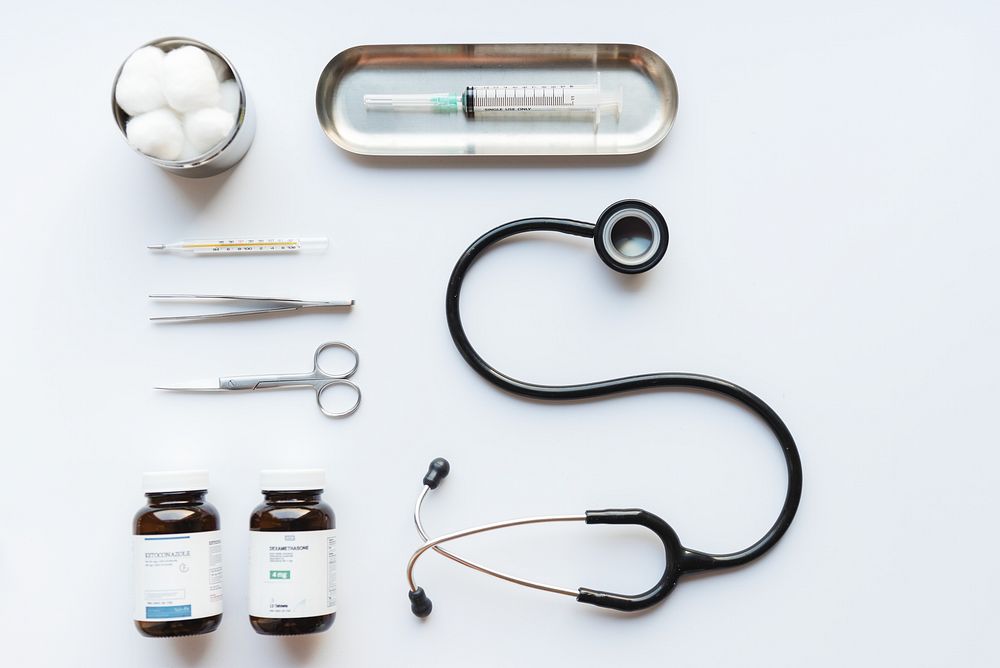 Medical tools on a white background, including a stethoscope, syringe, and scissors. Stethoscope and syringe are key medical…