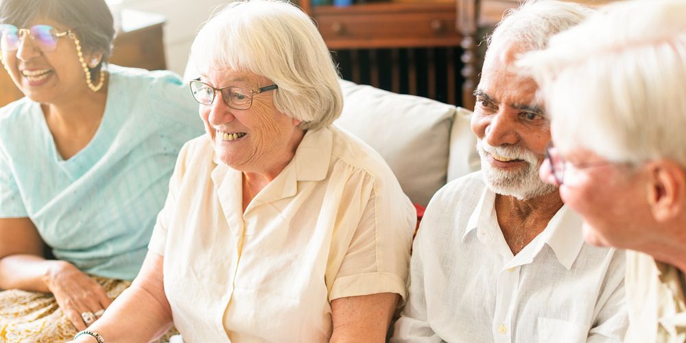 Group of diverse senior friends sitting on a couch, smiling and watching TV together. Diverse senior group enjoying time and…