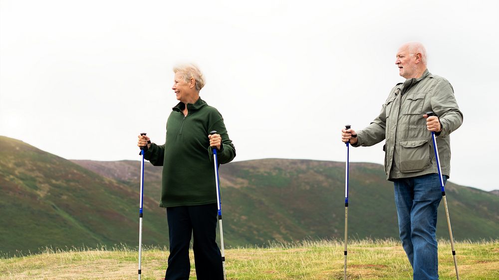 Senior couple hiking with poles in a scenic landscape. Seniors enjoying nature, hiking in the hills. Outdoor activity for…