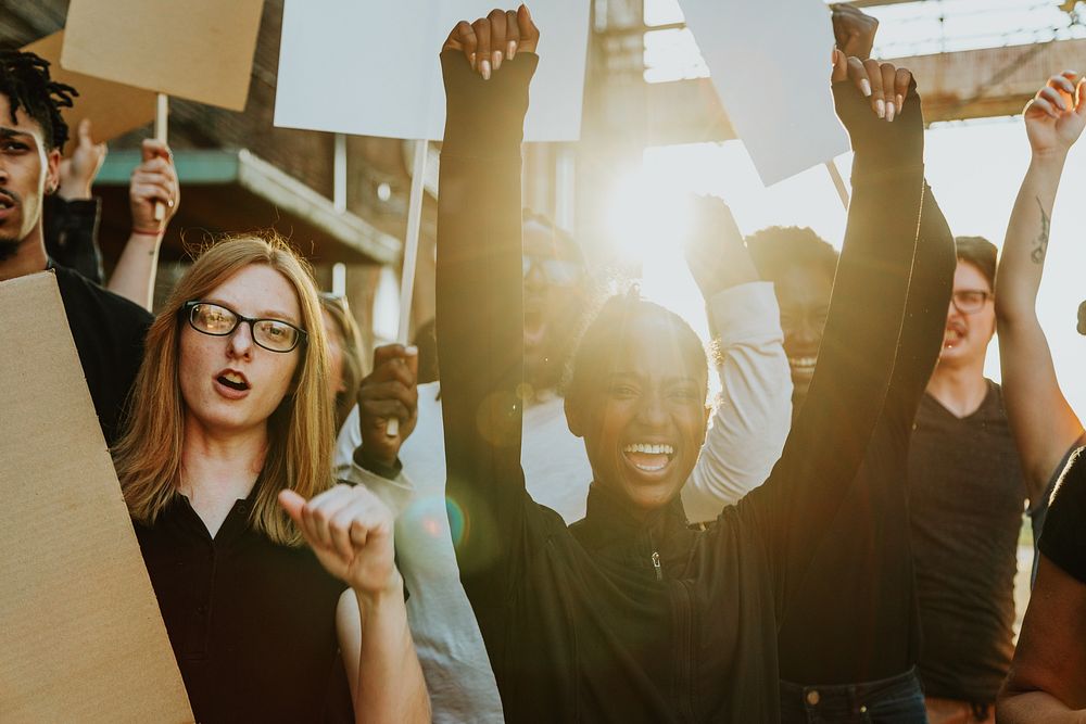 Group of happy diverse people at a protest, holding signs. Diverse people focused on protesting holding signs. Diverse men…