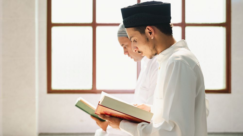 Two Muslim men reading the Quran during Ramadan, and praying in silence. Muslim men in traditional clothing studying Islam…