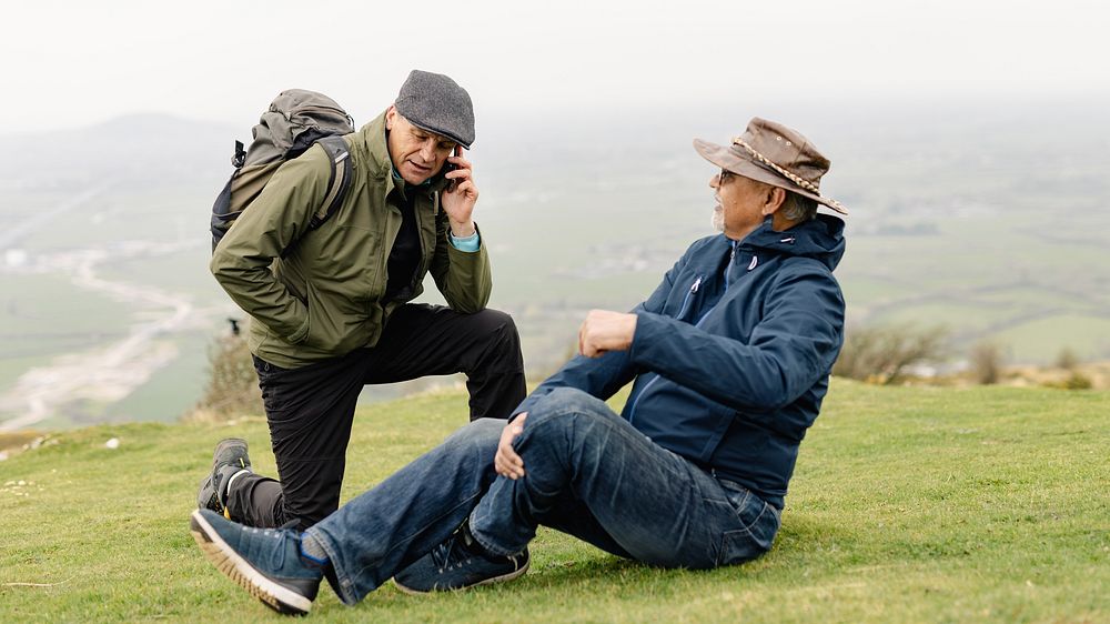 Senior man with injury during travel outdoors, scenic landscape with hills nature in the background. Senior man injure…