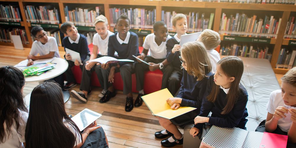 Diverse group of kids in a library, reading books together. Kids, books, and library setting create a vibrant learning…