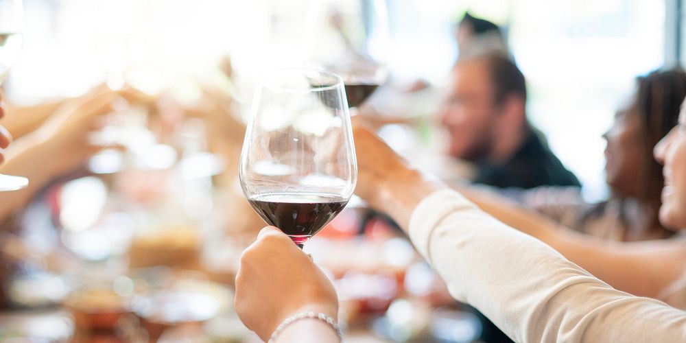 Group of people raising wine glasses in a toast. Diverse hands holding wine glasses. Celebration with wine, friends, and…