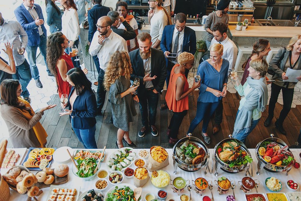 A vibrant gathering of diverse people enjoying a buffet. Men and women of various ethnicities socialize, savoring delicious…