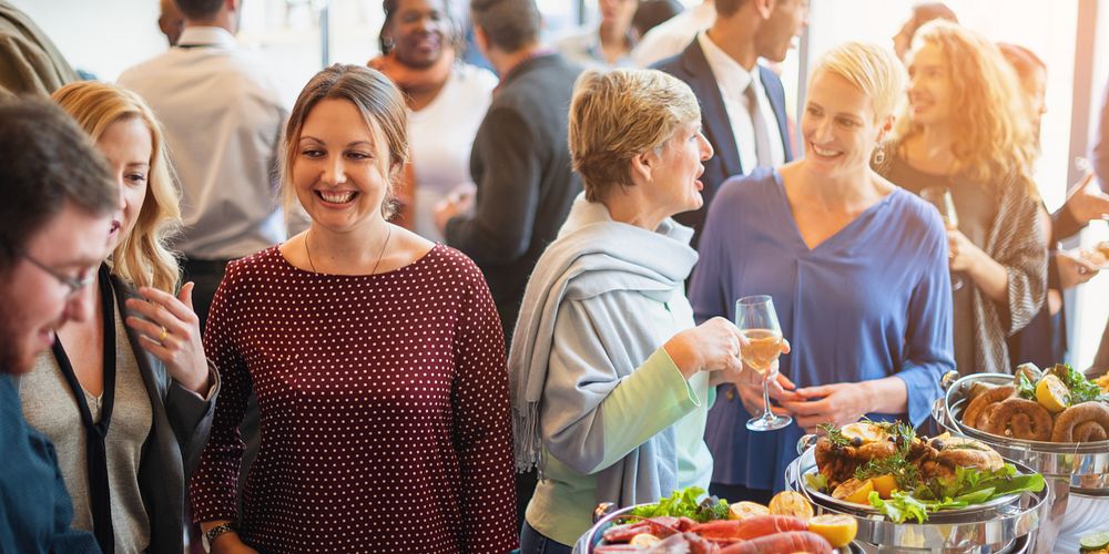 Group of diverse people at a buffet event, enjoying food and conversation. Social gathering with food, drinks, and diverse…