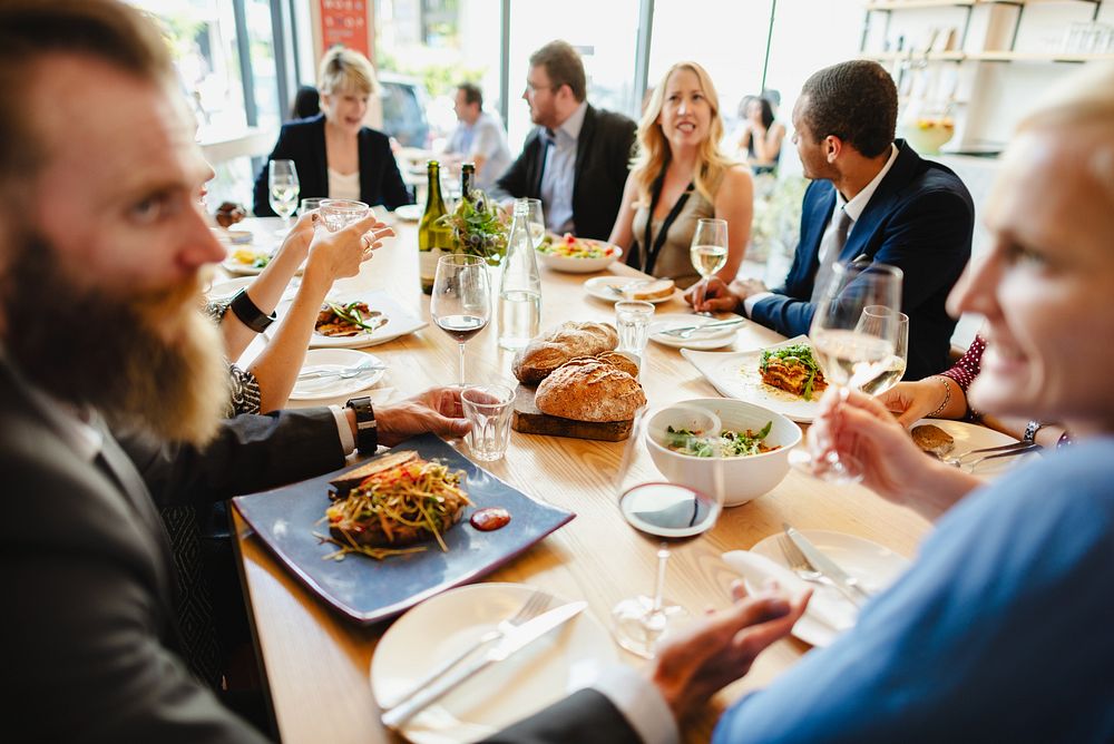 A diverse group of people enjoying a meal together at a stylish table share laughter and fine dining, celebrating friendship…