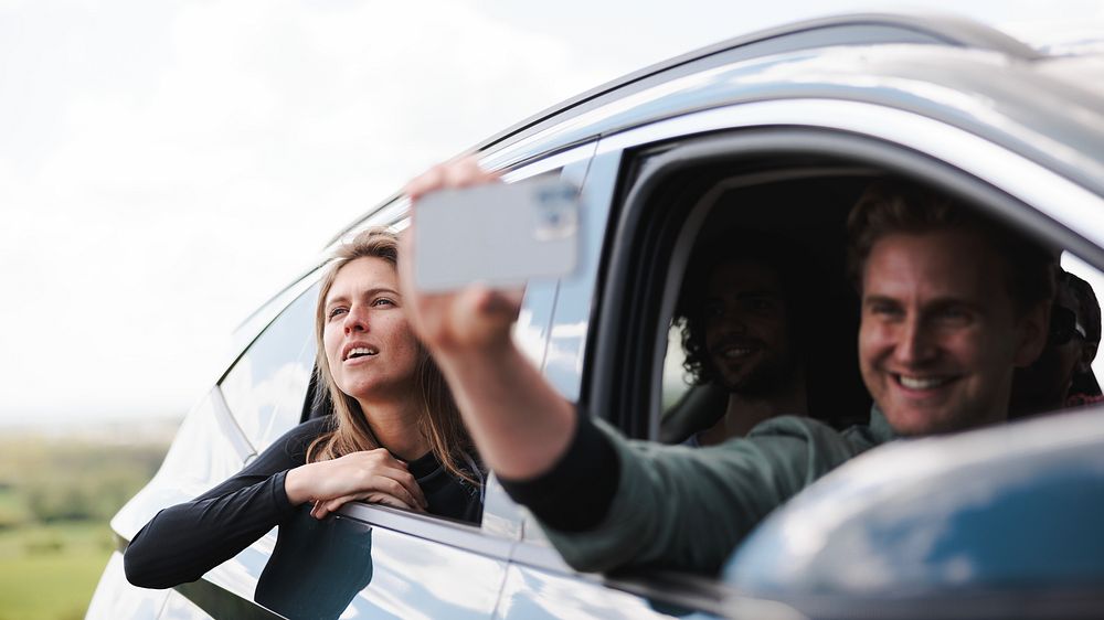 Group of friends taking a selfie from a car. Smiling people enjoying a road trip. Friends capturing moments on a road trip.…