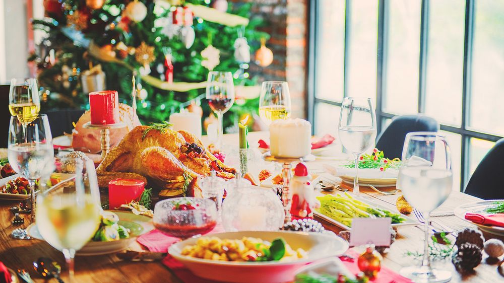 Festive holiday table with a Christmas tree, decorated with candles, wine glasses, and a turkey. Holiday feast with a…