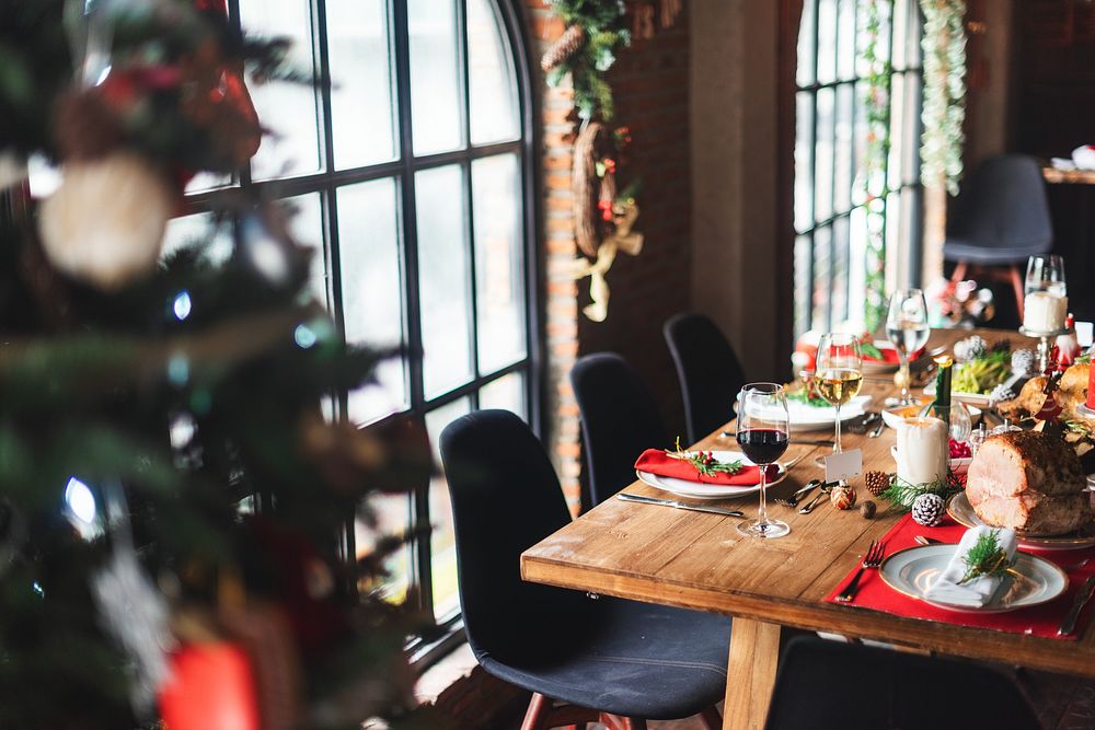 Festive dining table set for Christmas with holiday decor, wine glasses, and plates. Cozy Christmas atmosphere with festive…