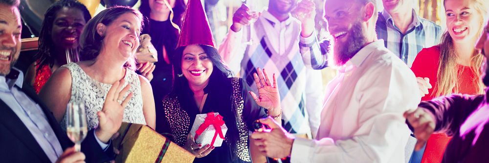 Group of diverse people celebrating at a party, smiling and exchanging gifts. Festive atmosphere with joyful expressions and…