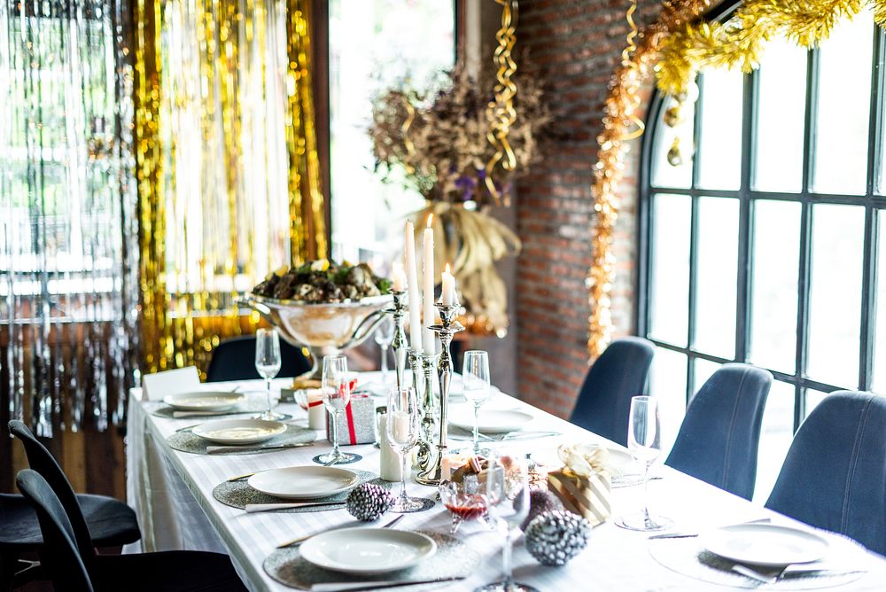 Elegant dining table set for a festive Christmas celebration with white tablecloth, candles, and decorations. Bright…