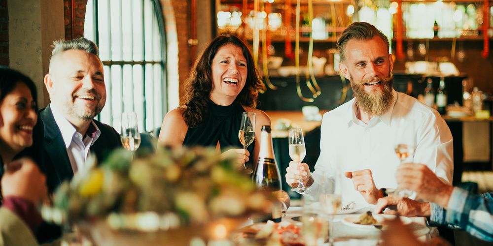 Group of diverse people enjoying a Christmas meal, laughing and toasting with champagne. Diverse group of people celebrating…