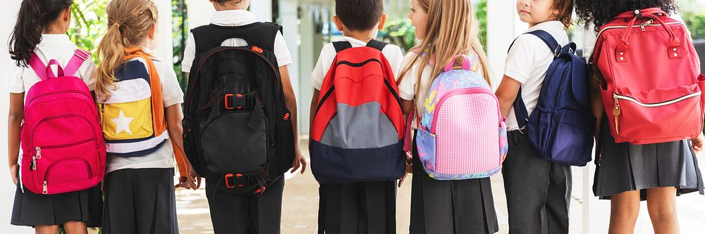 Children with backpacks, standing in a row. Diverse elementary students in school uniforms. Diverse group of kids elementary…