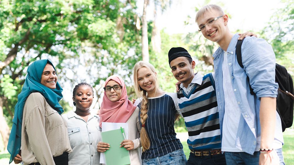 Diverse group of young adults smiling outdoors. Friends from various backgrounds, enjoying time together. Happy, diverse…