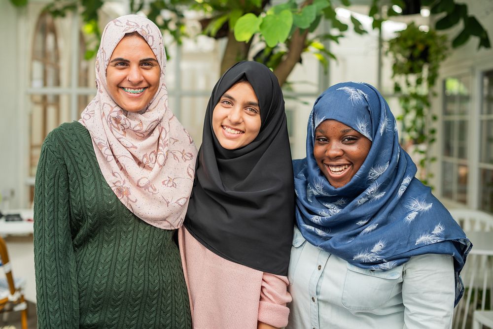 Three muslim women wearing hijabs smiling outdoors. Diverse group of women in hijabs. Women in hijabs enjoying time…