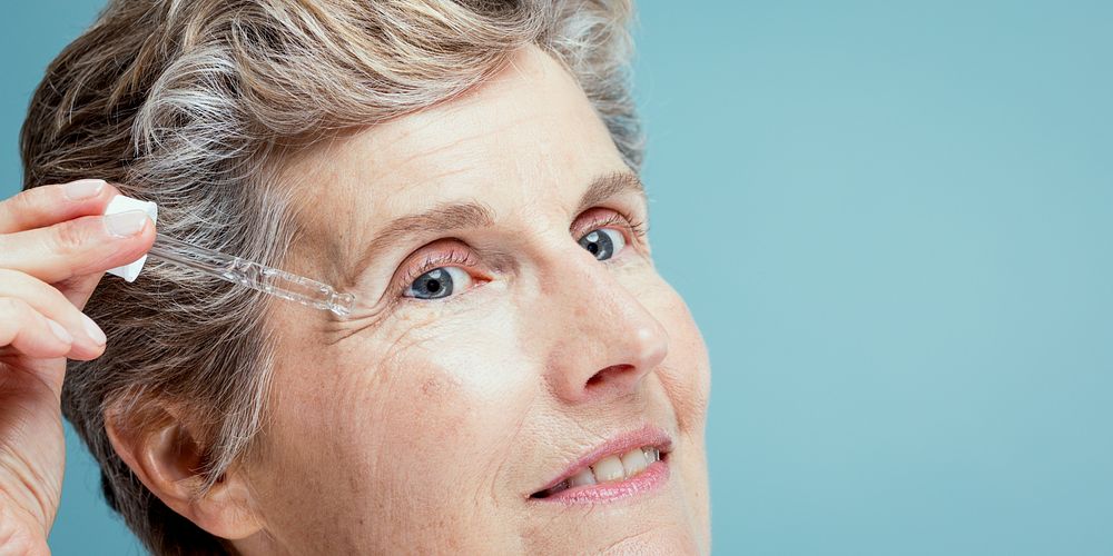 Elderly woman applying skincare serum with a dropper. Close-up of mature woman using serum. Skincare routine for older…