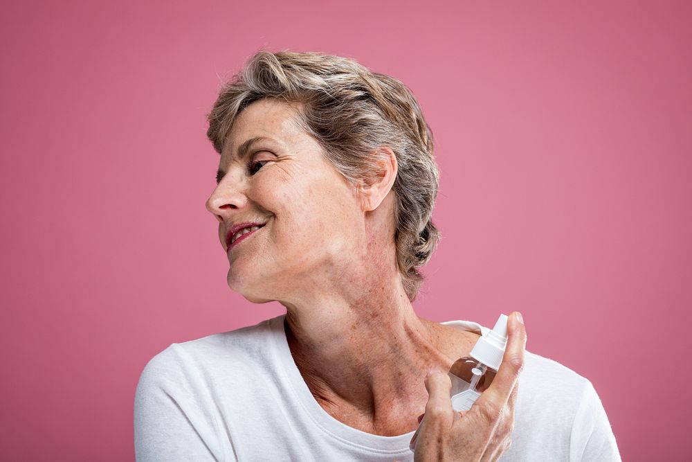 Smiling woman with short hair applying skincare. Mature woman enjoying skincare routine. Happy woman with skincare product…