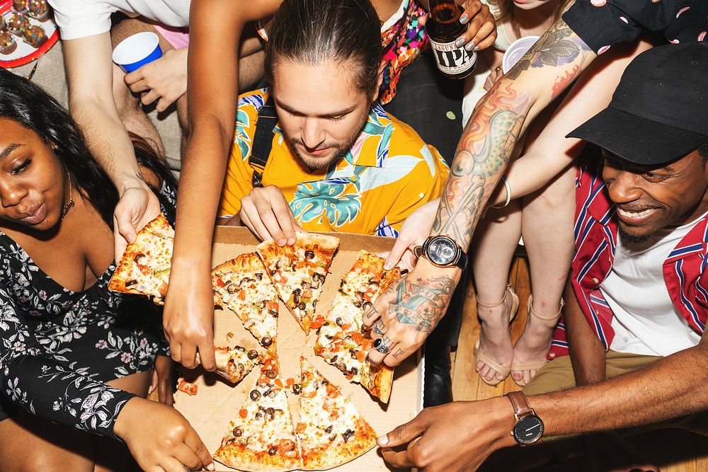 Group of friends enjoying pizza together. Diverse group sharing pizza slices. Hands reaching for pizza. Casual pizza party…