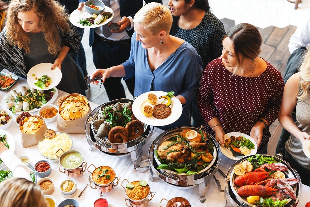 Diverse group of people enjoying buffet with various dishes. Diverse people serving food, buffet with salads, meats, and…