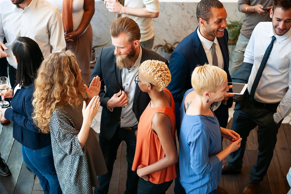 Diverse group at a social event, mingling and networking. People in business attire, engaging in conversation, holding…