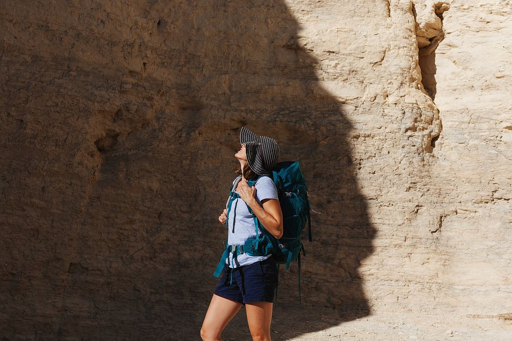 Person hiking in a desert canyon, wearing a hat and backpack. The hiker explores the rocky landscape, enjoying the adventure…