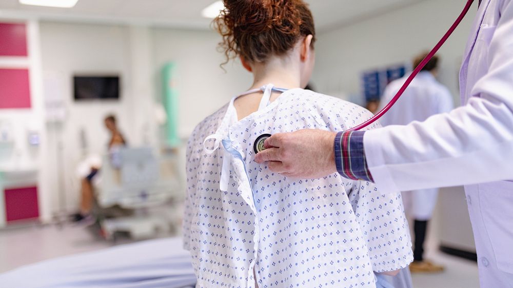 Doctor using stethoscope on patient in hospital. Medical check-up in clinical setting. Healthcare professional examining…