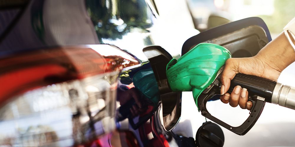 Close-up of a hand refueling a car with a green gas pump nozzle. Fueling a vehicle at a gas station. Gas pump, refueling…