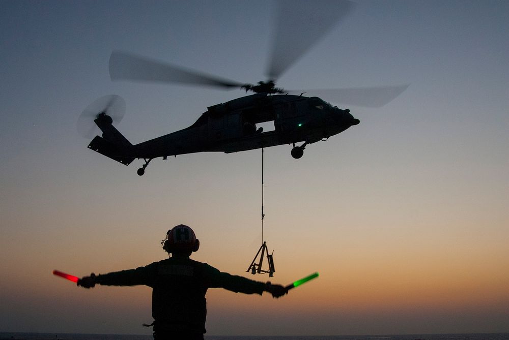 U.S. Navy Aviation Structural Mechanic Airman Jeremy Shadden signals the pilots of an MH-60S Seahawk helicopter assigned to…
