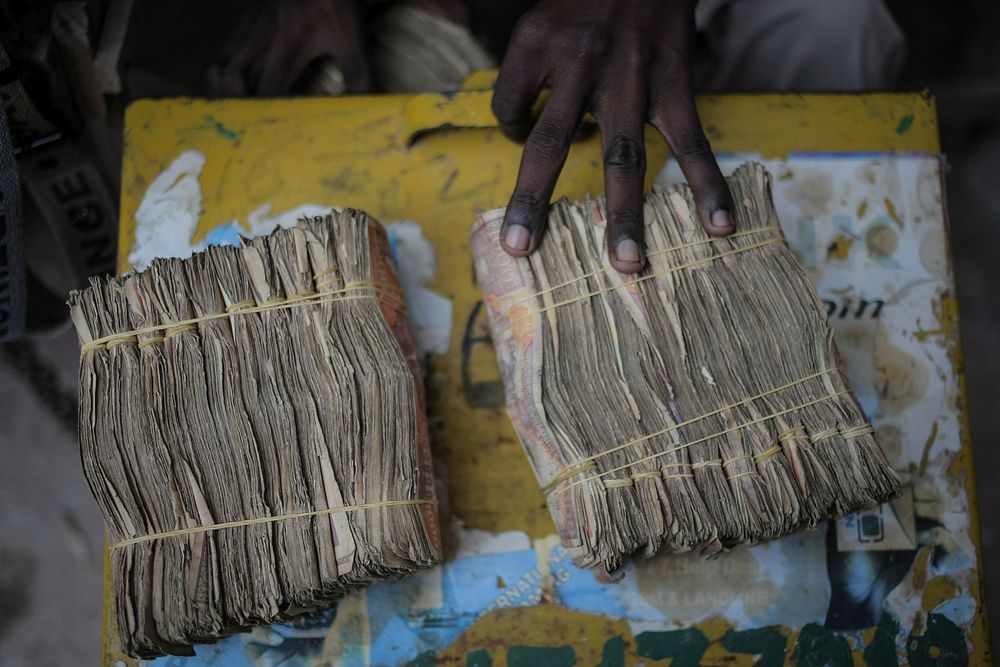 Money exchanger displays Somali shilling notes on the streets of the Somali capital Mogadishu. Original public domain image…