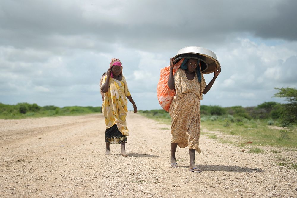 Women, walking with what possesions they can carry, arrive in a steady trickle at an IDP camp erected next to an AMISOM…