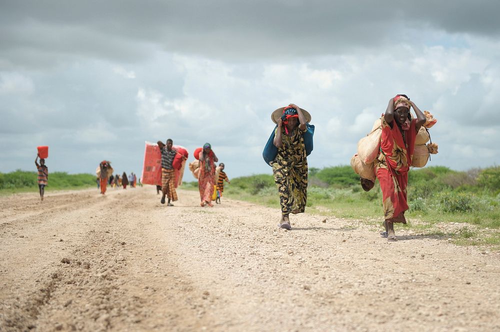 Women, walking with what possesions they can carry, arrive in a steady trickle at an IDP camp erected next to an AMISOM…