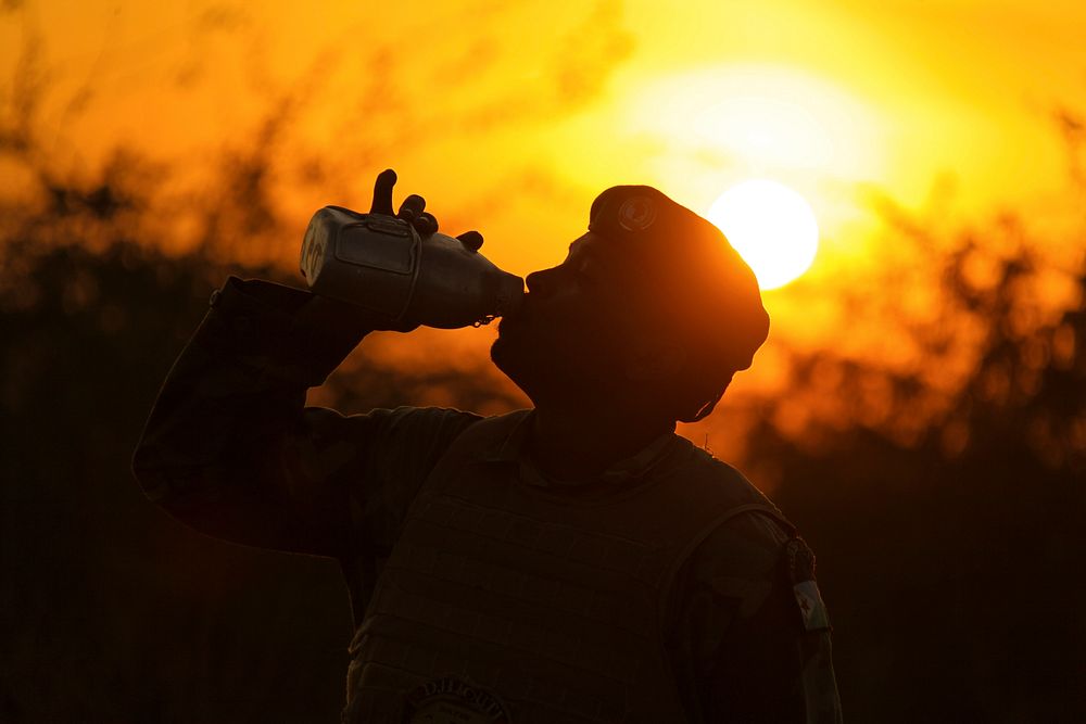 An AMISOM soldier belonging to the Djiboutian contingent of the mission drinks from his canteen as the sun sets over their…