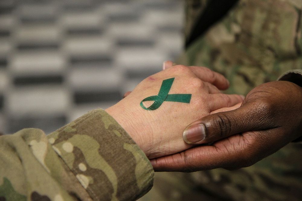 U.S. Army Sgt. 1st Class Tyrone Lawrence, right, places a temporary teal ribbon tattoo on a Soldier's hand at the Koele…
