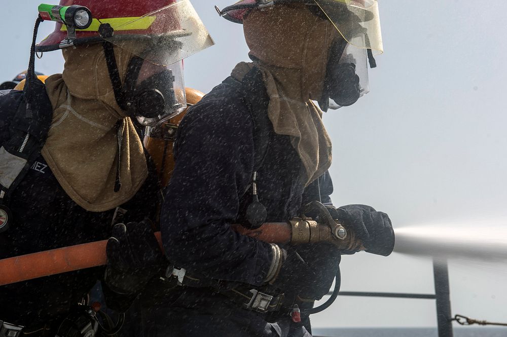 U.S. Sailors man a fire hose during a drill aboard the guided missile cruiser USS Philippine Sea (CG 58) in the Arabian Sea…