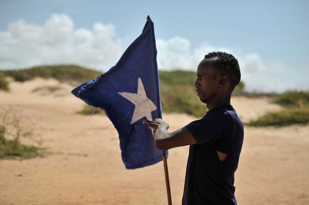 A young man carries the Somali flag while leading a group of soldiers during a demonstration by a local militia, formed in…