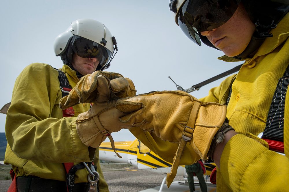 Veteran wildland firefighter rappeller Lacie England (right) checks a fellow rappeller's glove for good condition and proper…