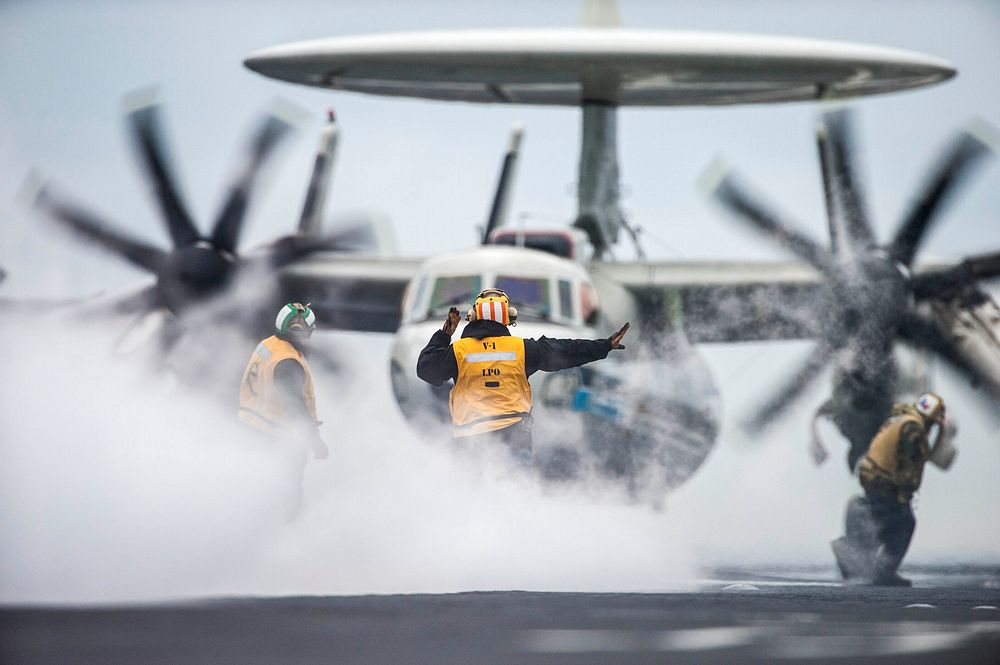 U.S. Sailors guide an E-2C Hawkeye aircraft assigned to Carrier Airborne Early Warning Squadron (VAW) 126 onto a catapult on…