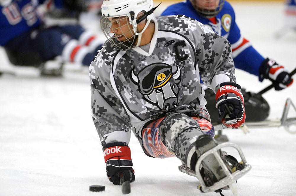 Army veteran Rico Roman of the San Antonio Rampage handles a puck during a sled hockey game with the USA Warriors in…